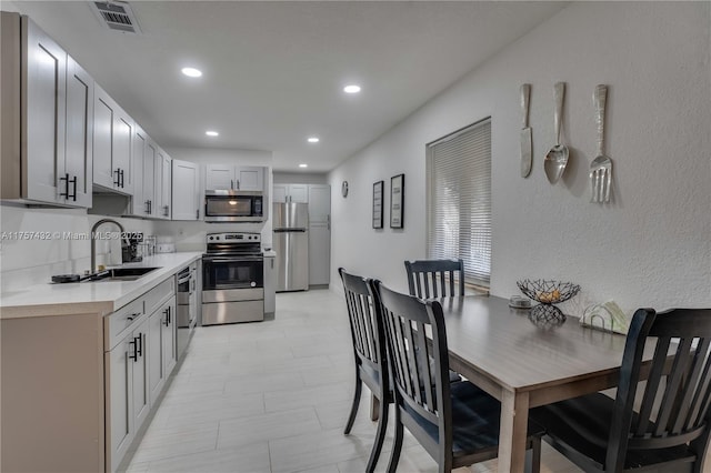 kitchen with visible vents, stainless steel appliances, light countertops, a sink, and recessed lighting