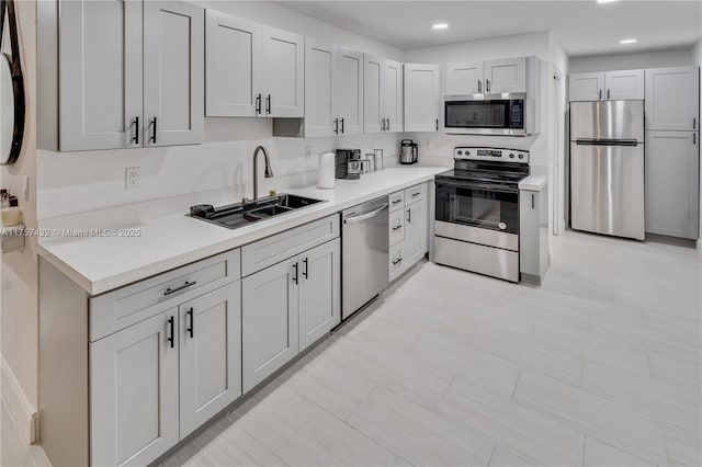 kitchen featuring stainless steel appliances, a sink, light countertops, and recessed lighting