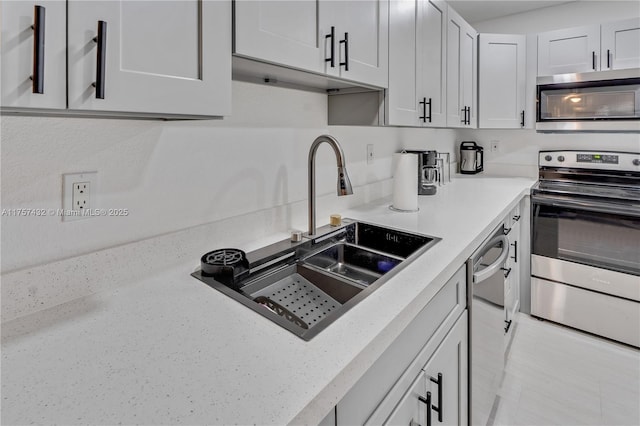 kitchen featuring white cabinets, stainless steel appliances, a sink, and light countertops