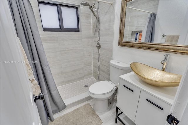 full bath with tiled shower, vanity, and toilet