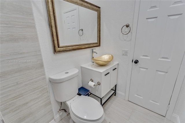 bathroom with a textured wall, vanity, and toilet