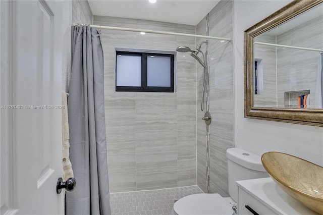 full bath featuring tiled shower, vanity, and toilet