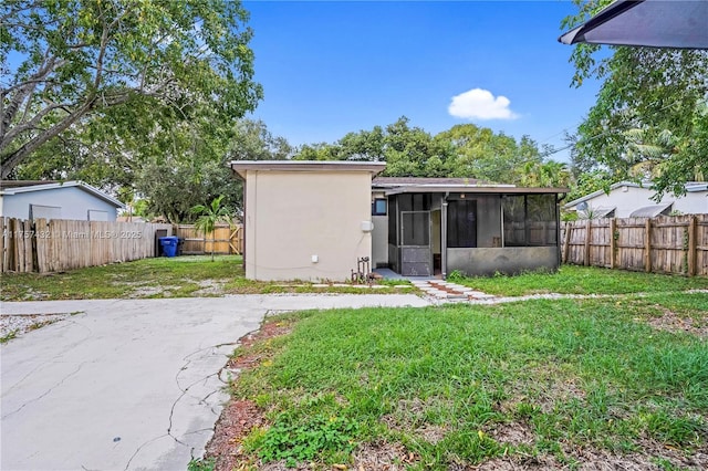 rear view of house featuring a lawn, a fenced backyard, and a sunroom