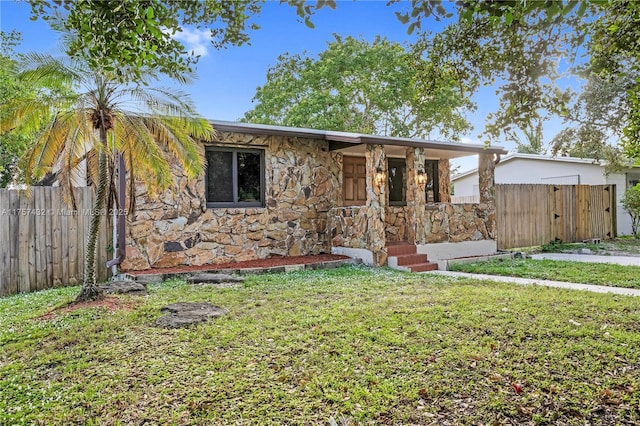 view of front of property with stone siding, fence, and a front lawn