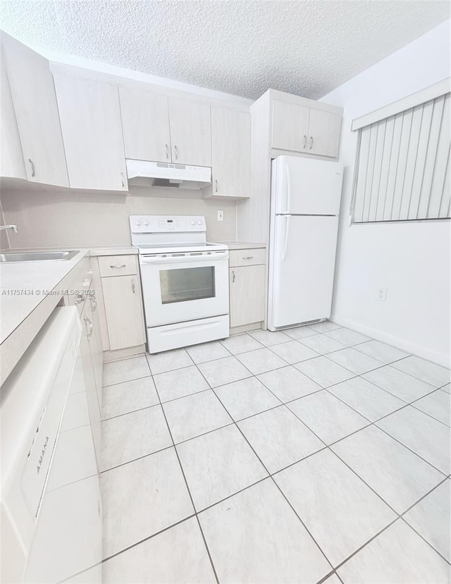 kitchen with white appliances, light countertops, under cabinet range hood, and a sink