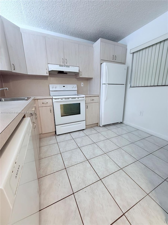 kitchen with under cabinet range hood, light countertops, light tile patterned flooring, white appliances, and a sink