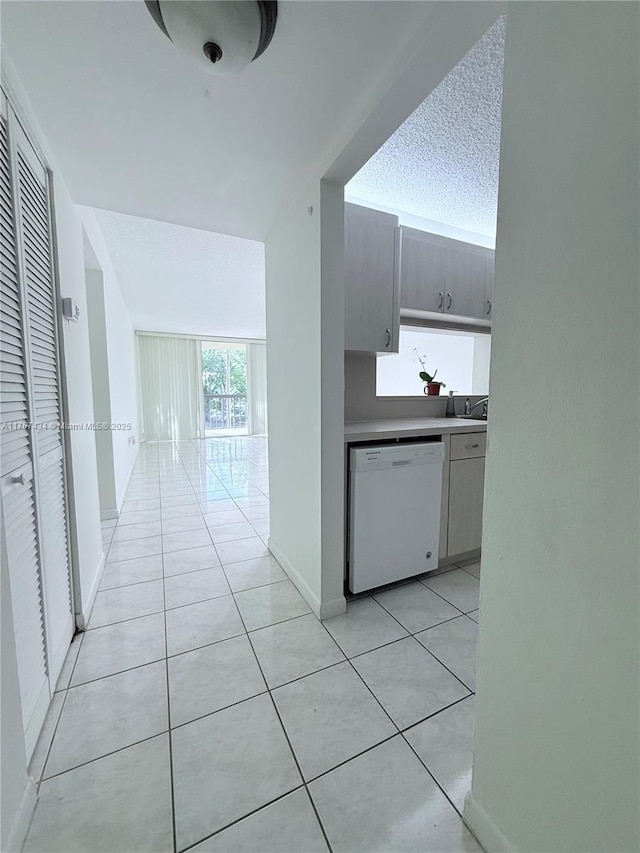 corridor featuring light tile patterned flooring, a textured ceiling, and baseboards