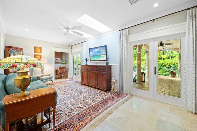 living area featuring ceiling fan, recessed lighting, a skylight, french doors, and wainscoting