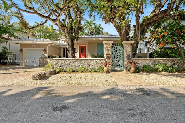 ranch-style house featuring stucco siding, driveway, a fenced front yard, metal roof, and a garage