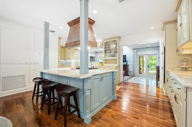 kitchen with visible vents, open shelves, a kitchen breakfast bar, tasteful backsplash, and wood finished floors