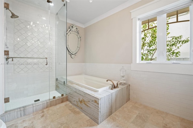bathroom with a stall shower, stone finish flooring, crown molding, a bath, and tile walls