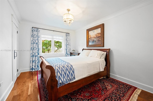 bedroom featuring a chandelier, crown molding, baseboards, and wood finished floors