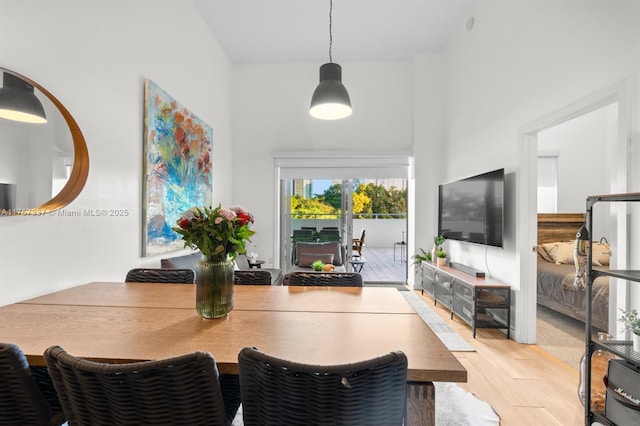 dining area with a towering ceiling and light wood-style flooring