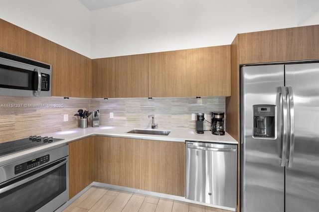 kitchen featuring tasteful backsplash, modern cabinets, stainless steel appliances, light countertops, and a sink