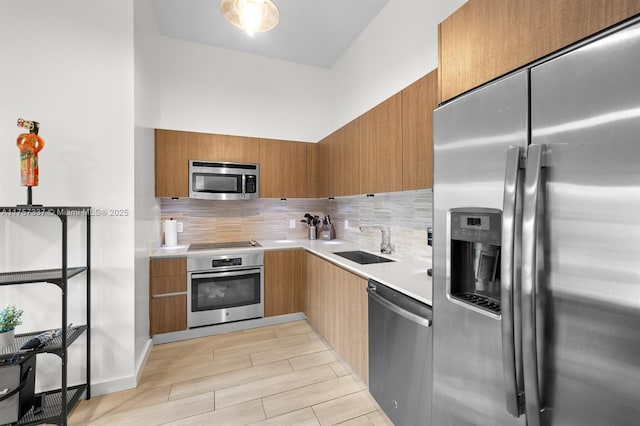 kitchen with light countertops, decorative backsplash, appliances with stainless steel finishes, a sink, and modern cabinets