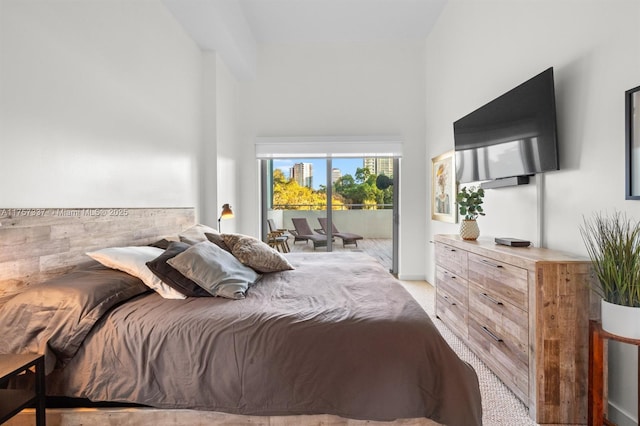 bedroom with light carpet, access to outside, and a towering ceiling