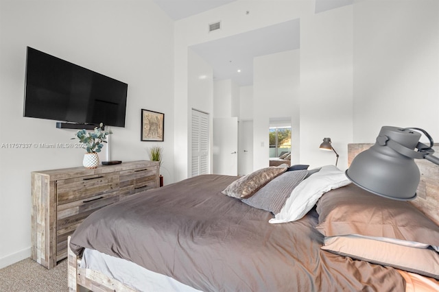 carpeted bedroom with baseboards, a high ceiling, visible vents, and a closet