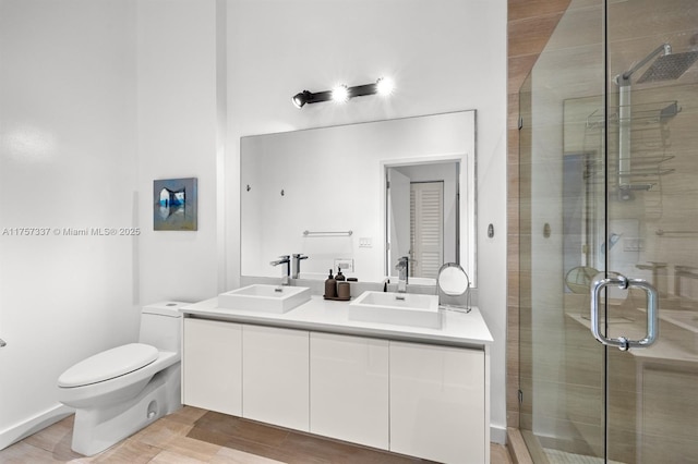 bathroom featuring a sink, a shower stall, toilet, and double vanity