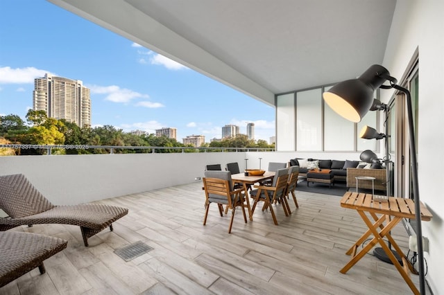 view of patio with a view of city, visible vents, a balcony, and an outdoor hangout area