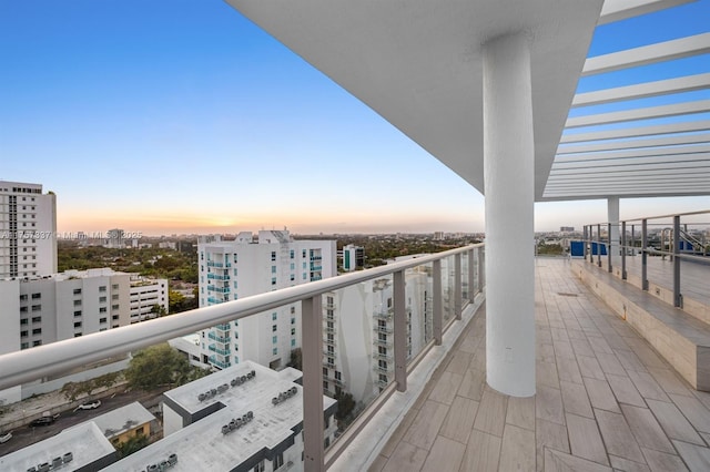 balcony at dusk featuring a view of city