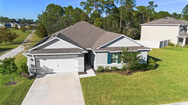 view of front of property with concrete driveway, roof with shingles, an attached garage, a front yard, and stucco siding