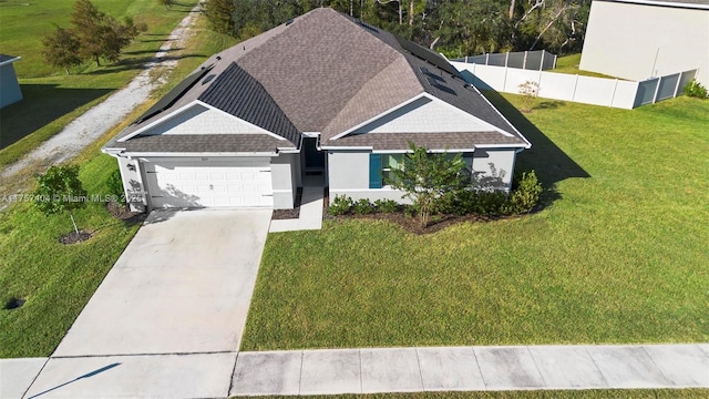 view of front of home with roof with shingles, concrete driveway, a front yard, fence, and a garage