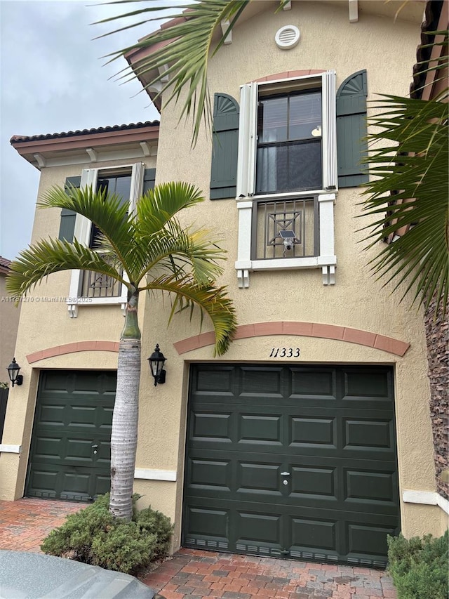 exterior space featuring a garage, decorative driveway, and stucco siding