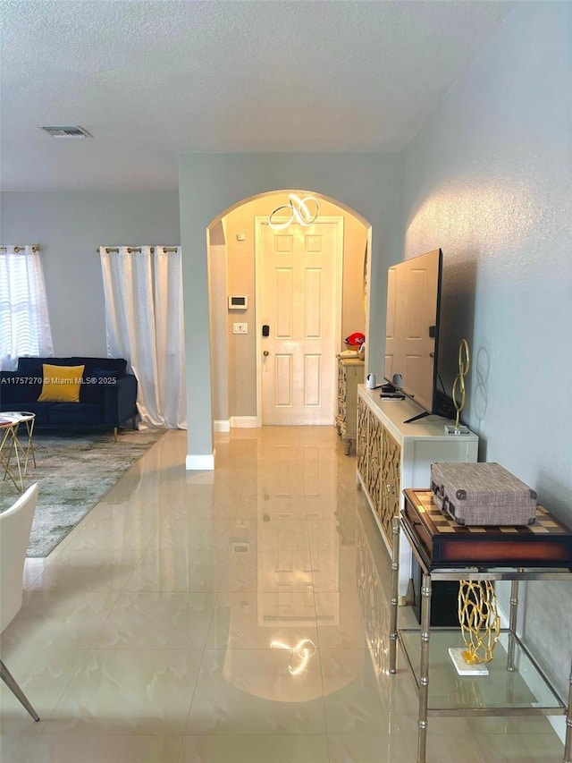 foyer with arched walkways, visible vents, and a textured ceiling