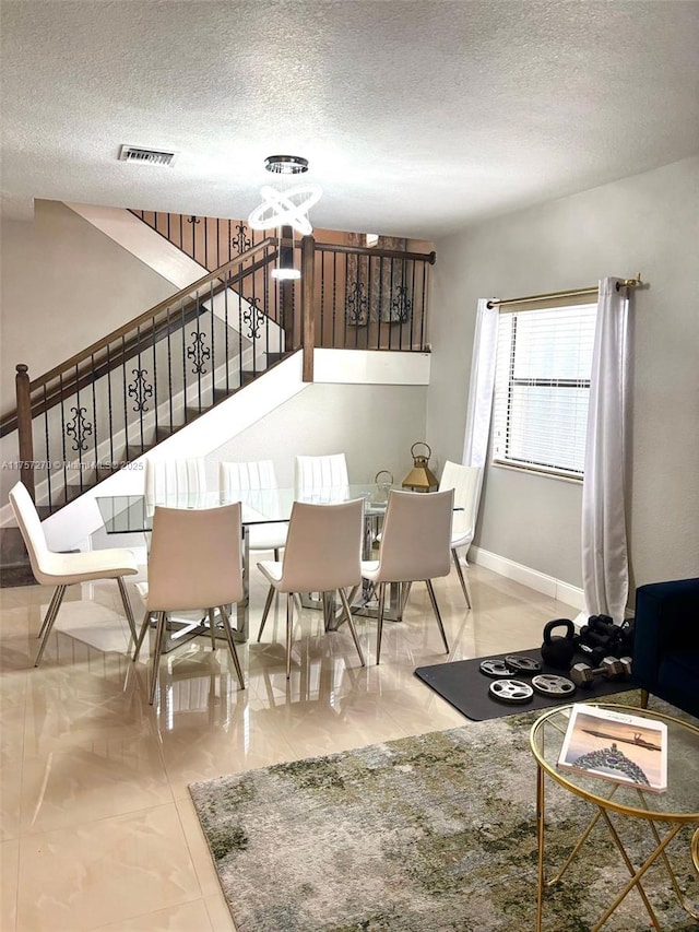 dining area featuring visible vents, stairway, and a textured ceiling