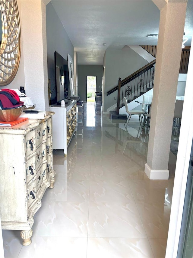 corridor with baseboards, stairs, and visible vents