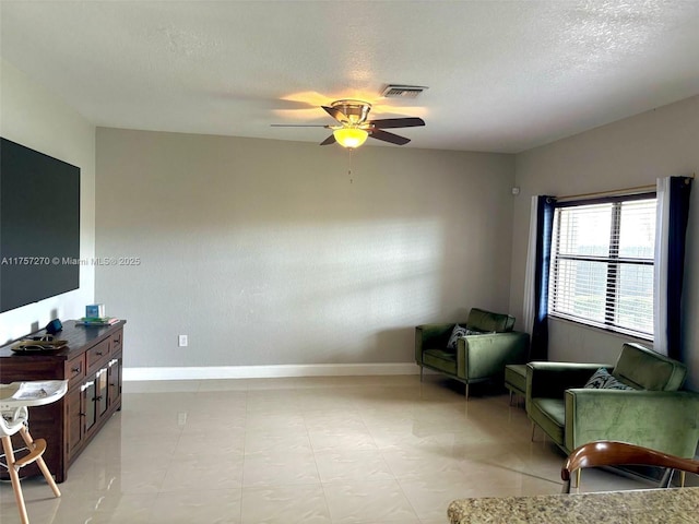 sitting room with a textured ceiling, baseboards, visible vents, and a ceiling fan