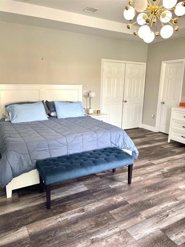 bedroom featuring a notable chandelier, wood finished floors, visible vents, baseboards, and a closet