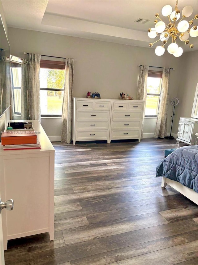 bedroom with a notable chandelier, dark wood-style flooring, visible vents, baseboards, and a raised ceiling