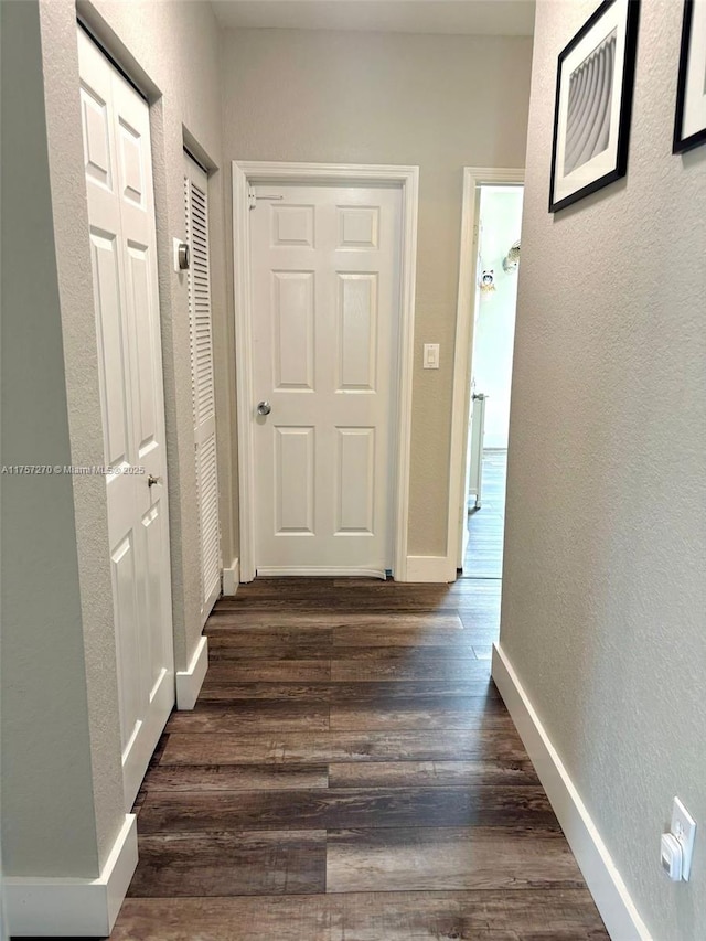 hall with baseboards, dark wood-style flooring, and a textured wall