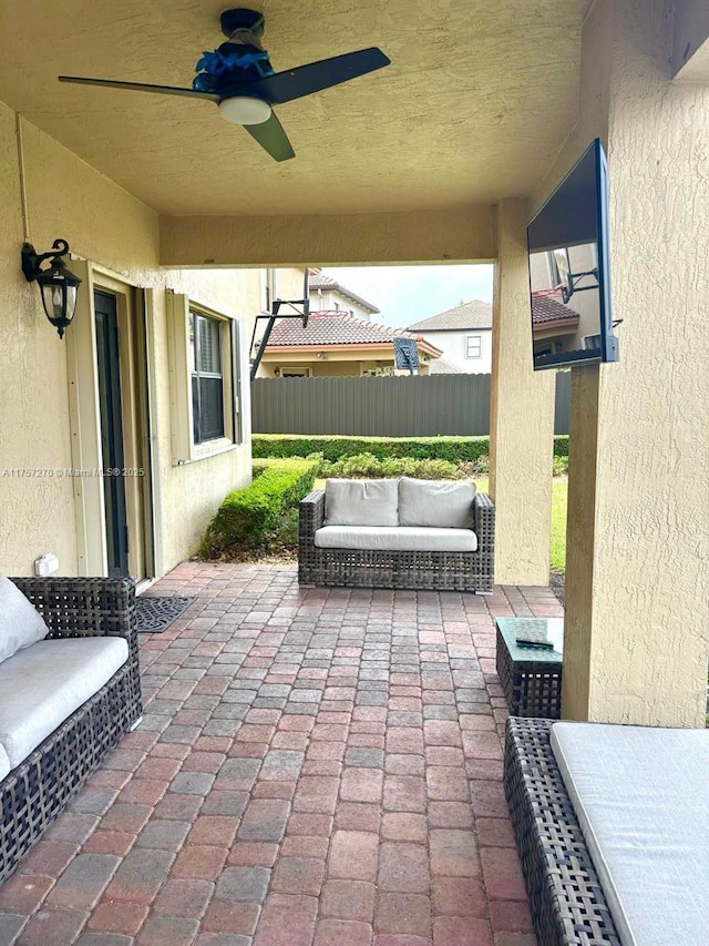 view of patio featuring ceiling fan, fence, and an outdoor living space