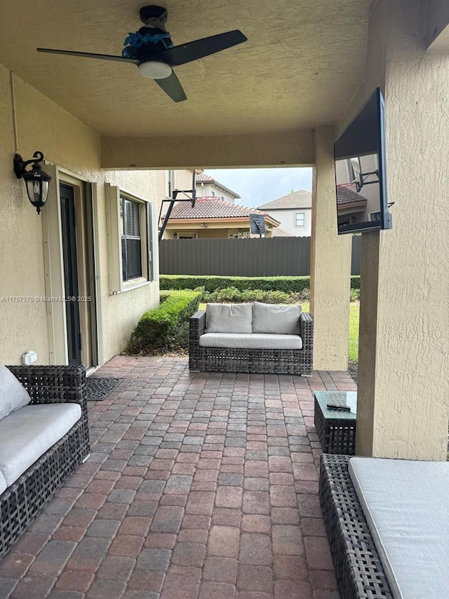 view of patio with outdoor lounge area, fence, and ceiling fan