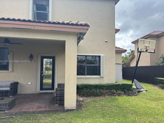 entrance to property with a yard, a tile roof, fence, and stucco siding