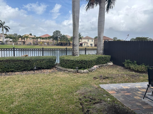 view of yard featuring a water view, fence, and a patio