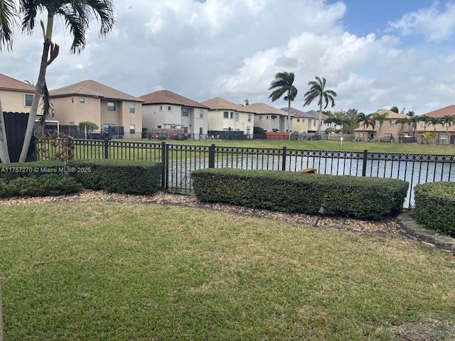 view of yard featuring a water view, a residential view, and fence