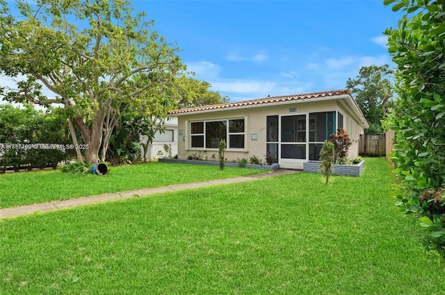 rear view of house with a garage, a lawn, a sunroom, a tiled roof, and stucco siding