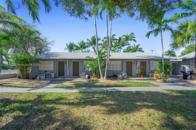 ranch-style house featuring a front lawn and stucco siding