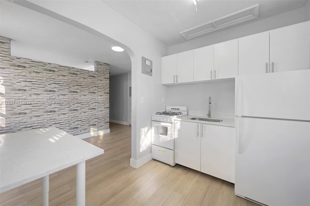 kitchen featuring light wood-style flooring, white appliances, a sink, white cabinets, and light countertops