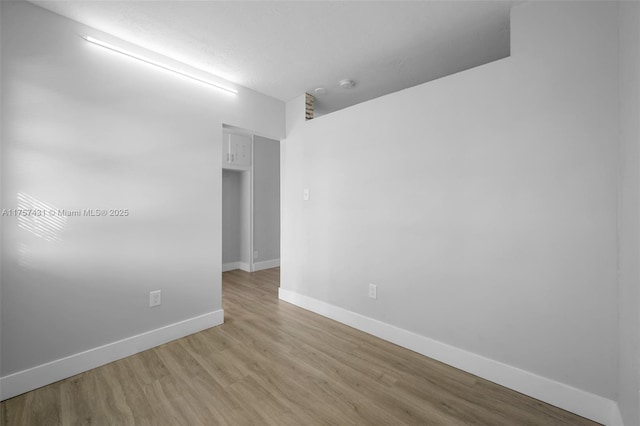 unfurnished room with baseboards and wood finished floors