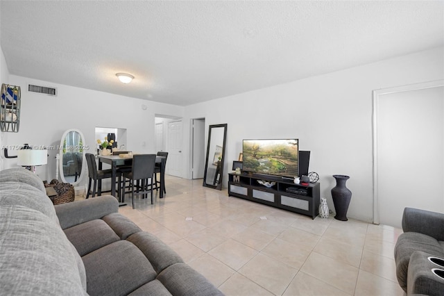 living room with visible vents, a textured ceiling, and light tile patterned flooring