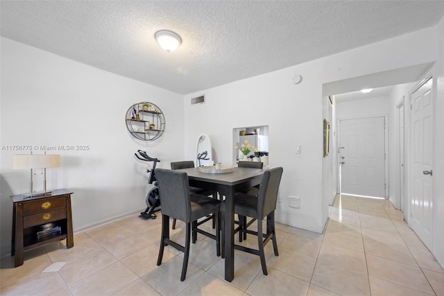 dining area with visible vents, a textured ceiling, and light tile patterned flooring