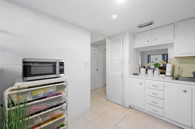 kitchen with tasteful backsplash, light countertops, stainless steel microwave, visible vents, and a sink