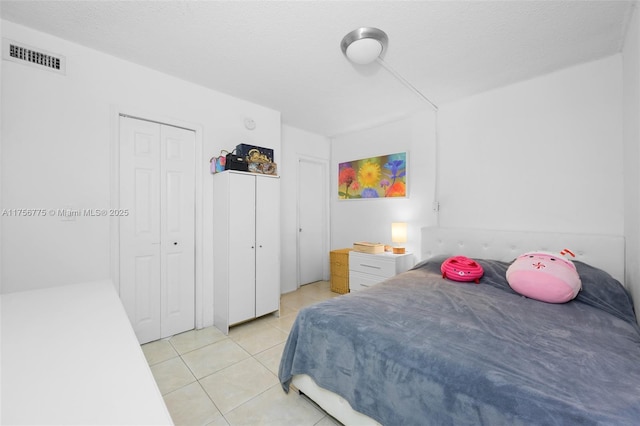 bedroom featuring a closet, light tile patterned flooring, and visible vents