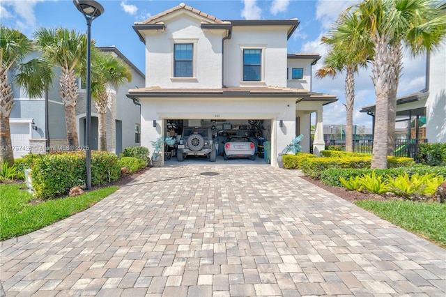 view of front of house featuring a garage, decorative driveway, a tile roof, and stucco siding