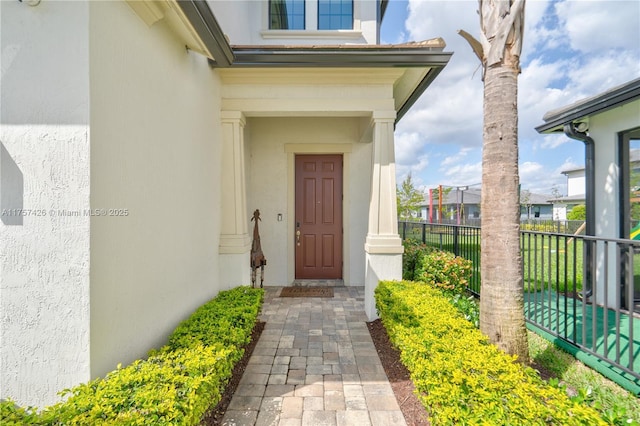 property entrance featuring fence and stucco siding