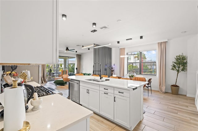 kitchen featuring light countertops, a sink, white cabinetry, and a healthy amount of sunlight